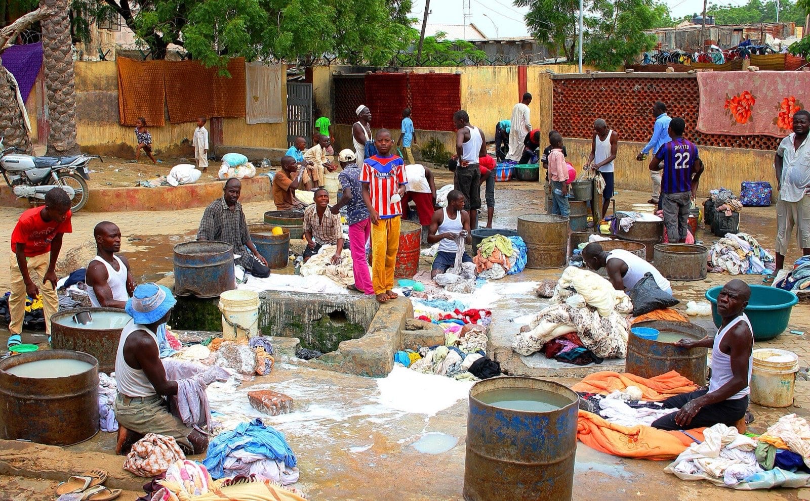Men working over a row of sunken indigo dye pits, cloth draped at the edges.