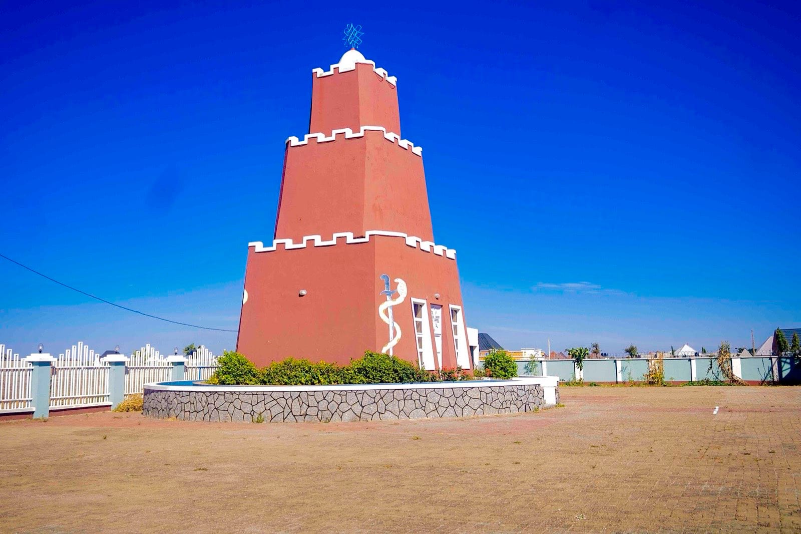 A tall square mud-brick minaret against a clear blue sky.