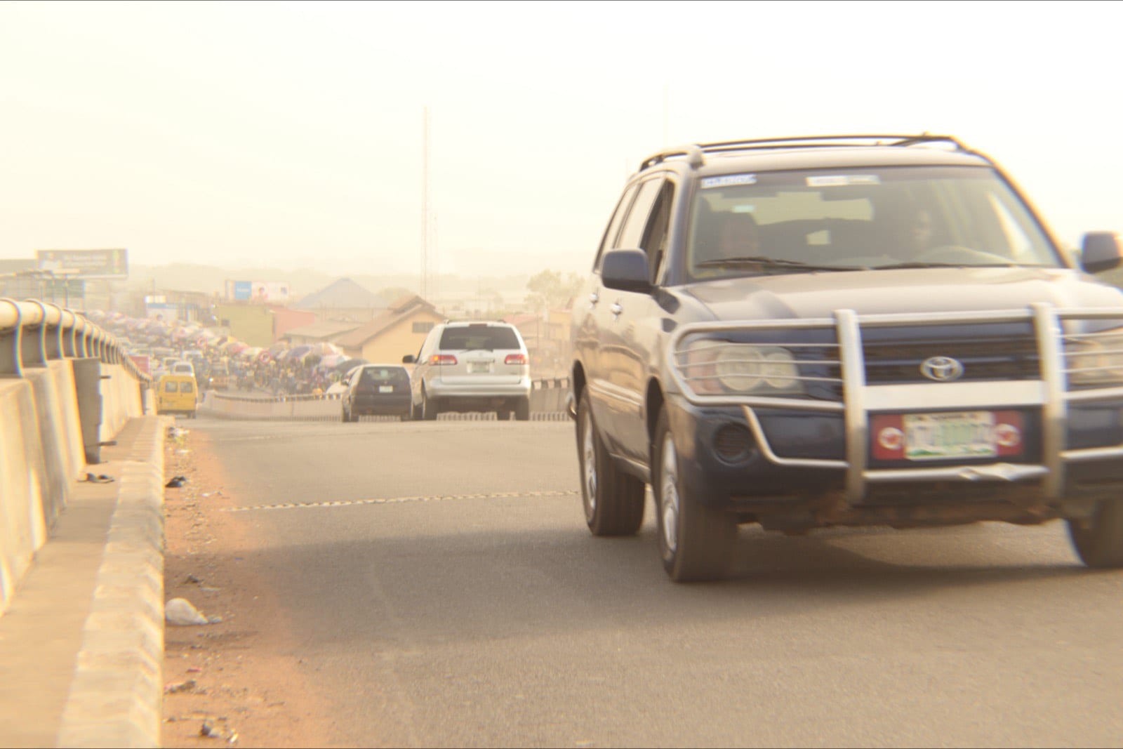 Cars and minibuses along a broad road running through Ilorin.