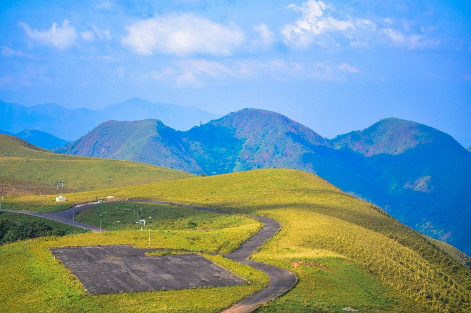 Grassland and hills on the Obudu plateau, with a helipad in the foreground.