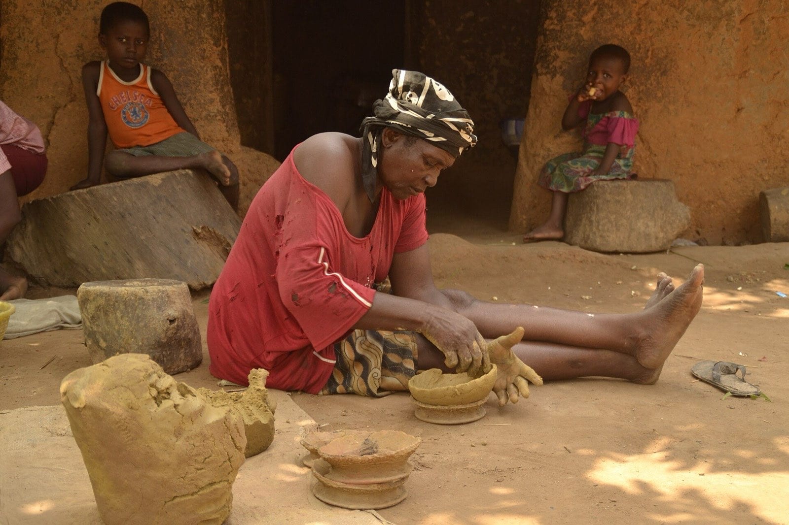 A potter beginning to mould a clay pot by hand.