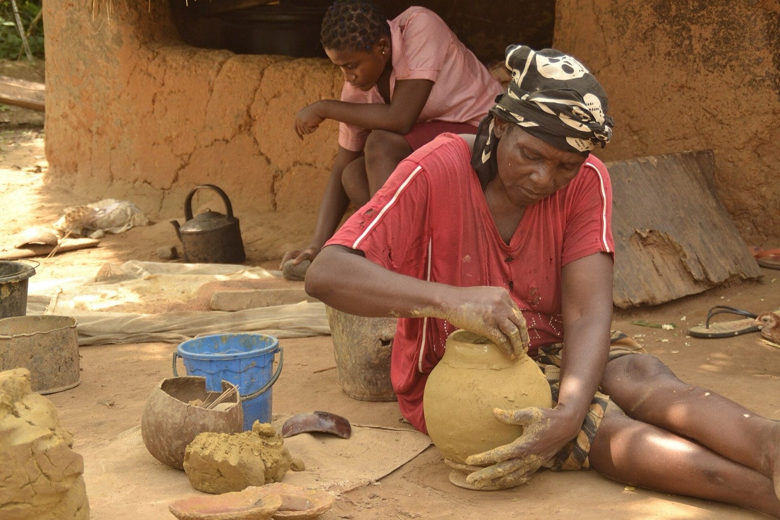A potter shaping the mouth of a clay pot.
