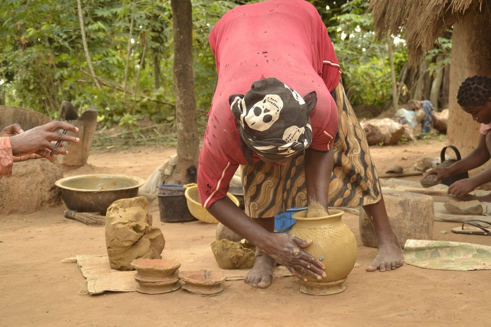 A spiral metal tool being rolled around a pot to work a pattern into it.