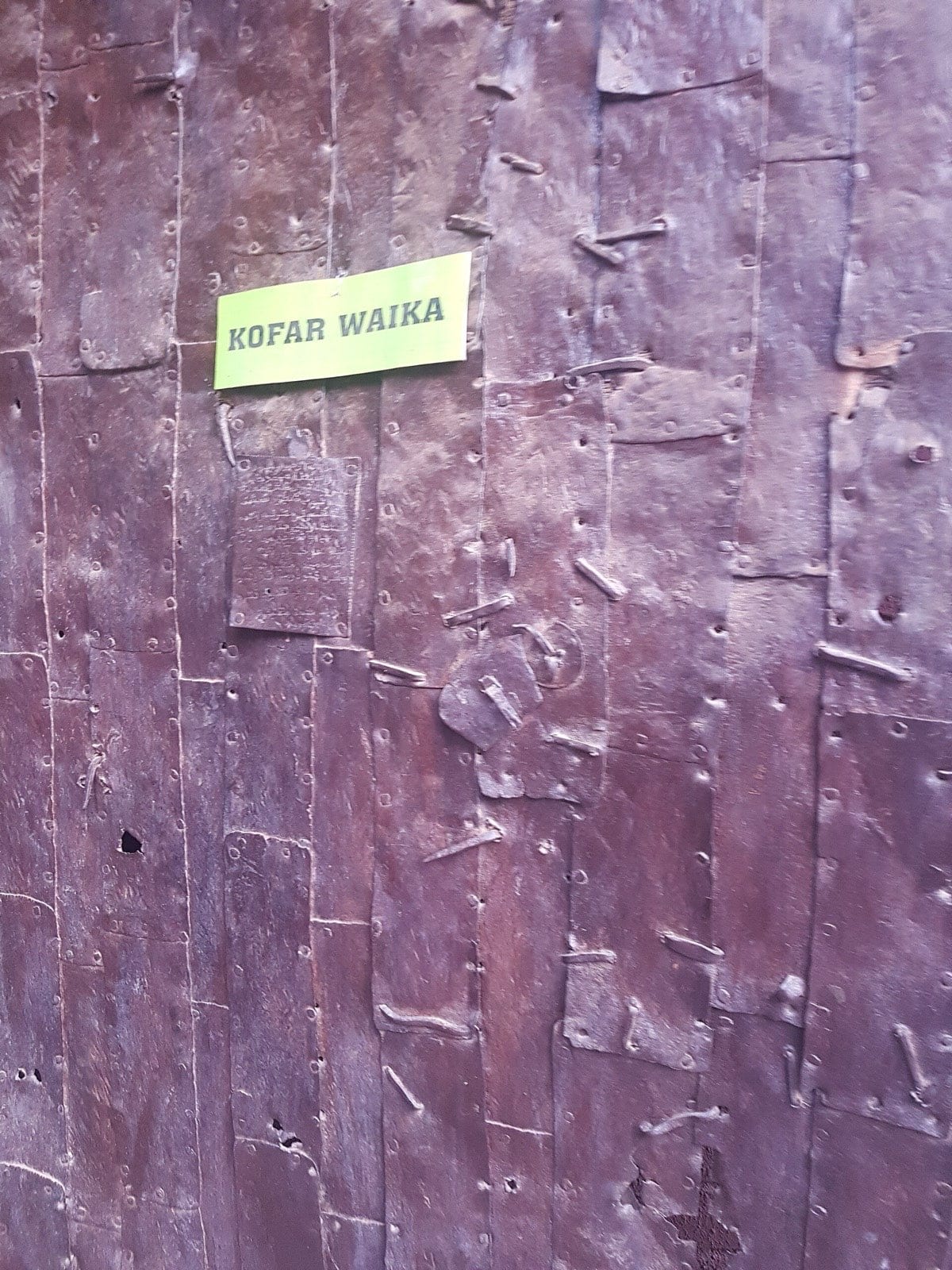 A mud-walled gateway standing in an opening in an earth city wall.