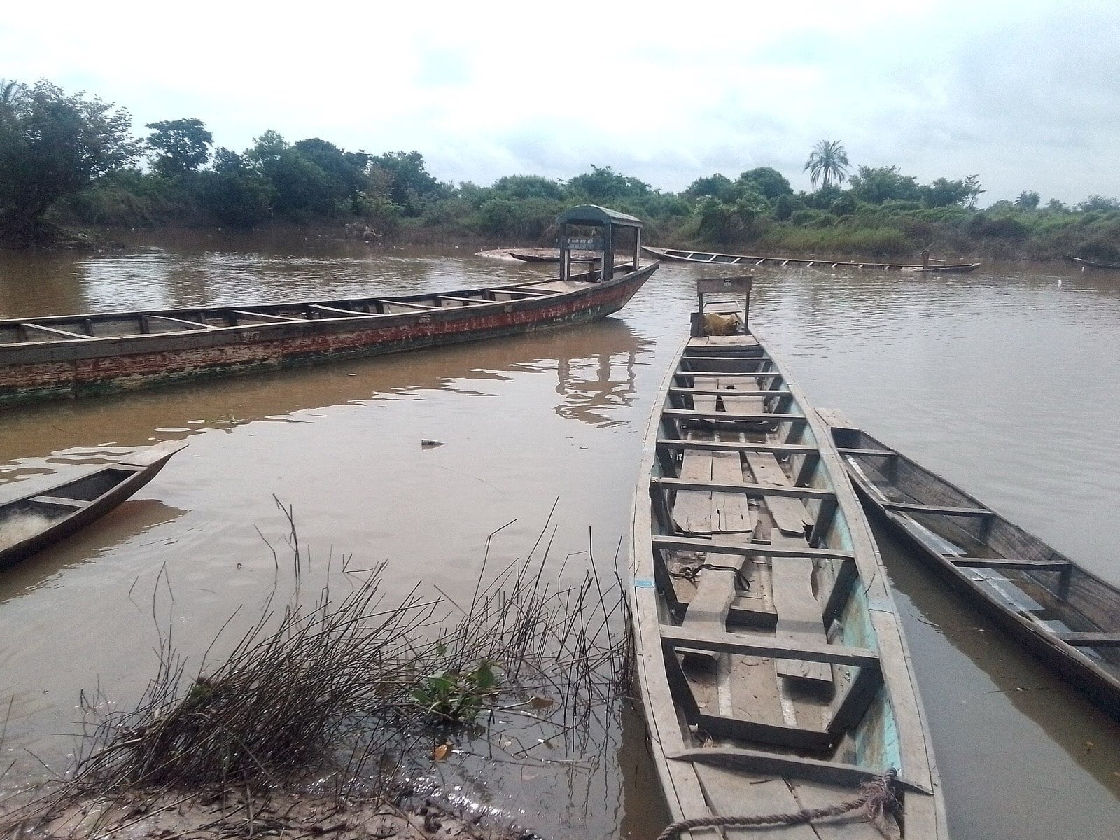 Hand-built wooden fishing boats drawn up on a riverbank.