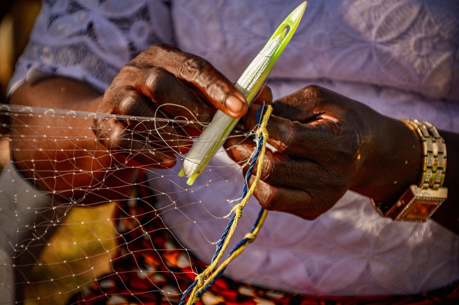 A woman weaving a fishing net by hand.